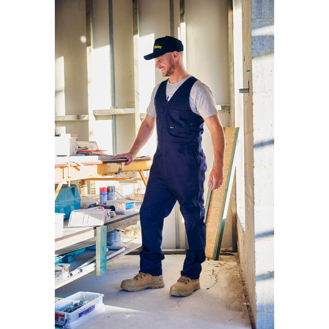 Man in blue overalls, wearing a Bisley BCAP50 Cap, standing in a workshop.