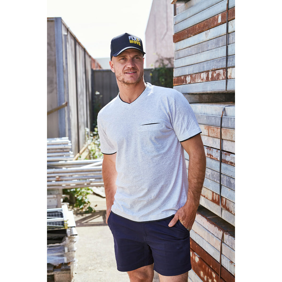 Man wearing a Bisley BCAP70 cap, t-shirt and navy shorts standing outdoors with stacked scaffolding in the background.