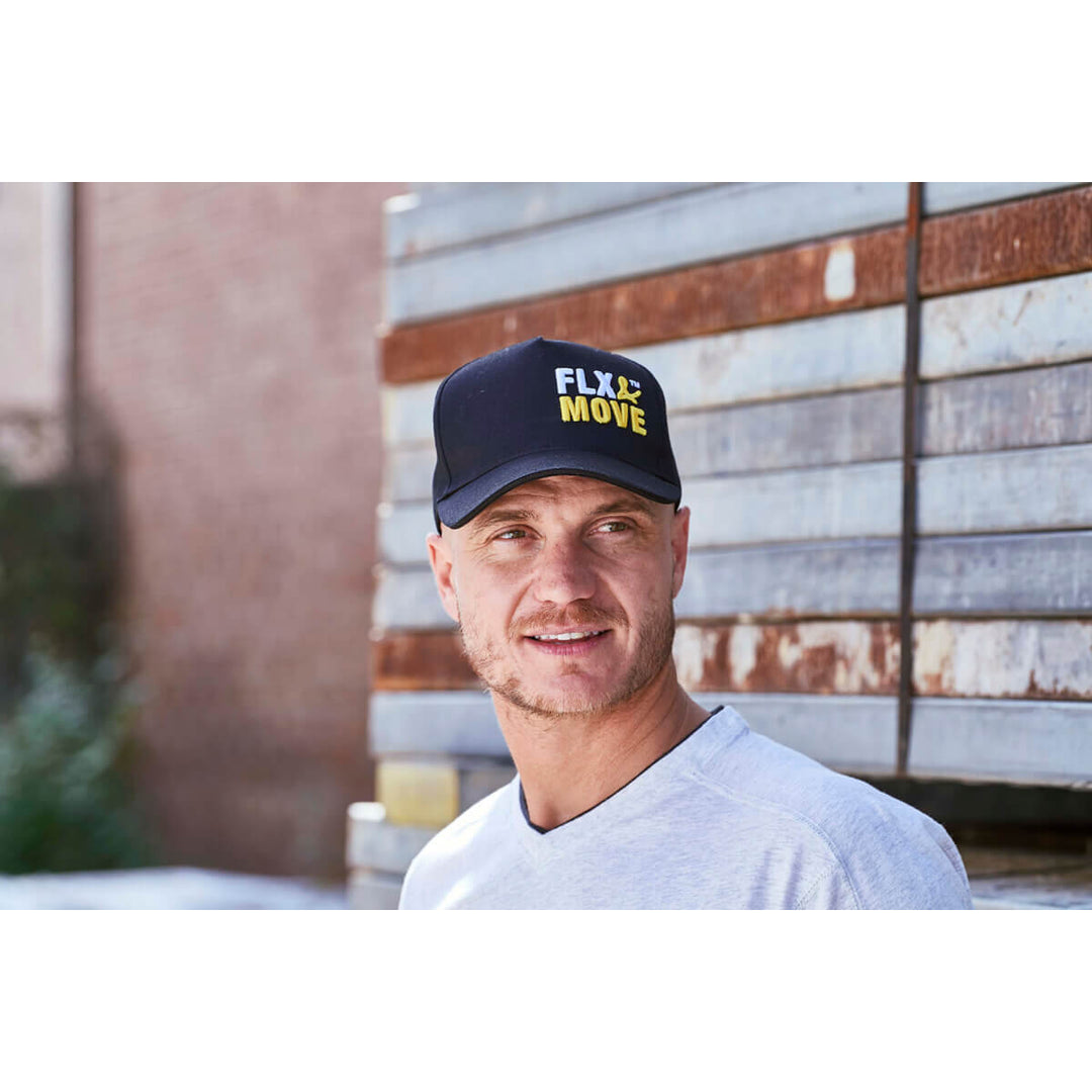 Man wearing a Bisley BCAP70 cap with 'FLX MOVE' logo in front of a rustic wall.